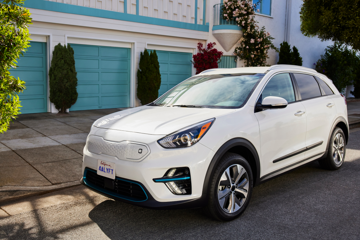 Photo of a white electric car parked in front of a house.  